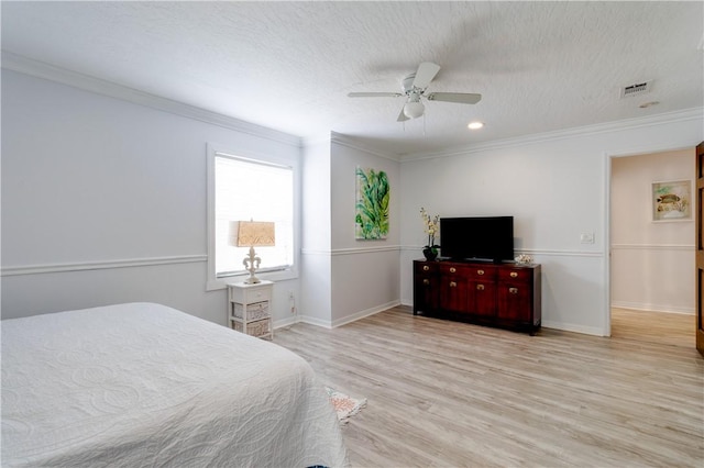 bedroom with ceiling fan, ornamental molding, light hardwood / wood-style floors, and a textured ceiling