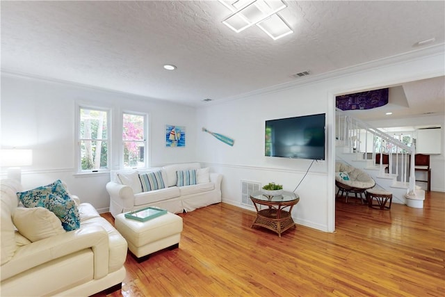 living room featuring wood-type flooring, crown molding, and a textured ceiling