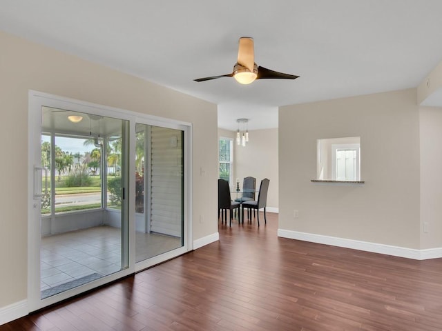 spare room featuring dark hardwood / wood-style flooring and ceiling fan with notable chandelier