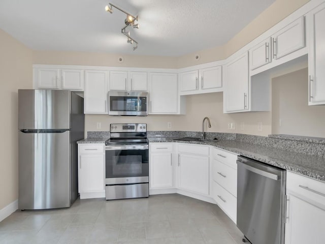 kitchen with light stone countertops, sink, a textured ceiling, white cabinets, and appliances with stainless steel finishes