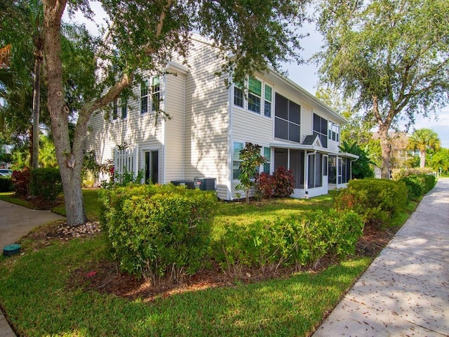 view of side of home featuring central AC, a sunroom, and a yard