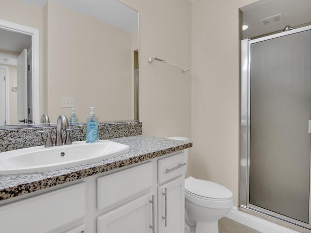 bathroom featuring vanity, toilet, and a shower with shower door