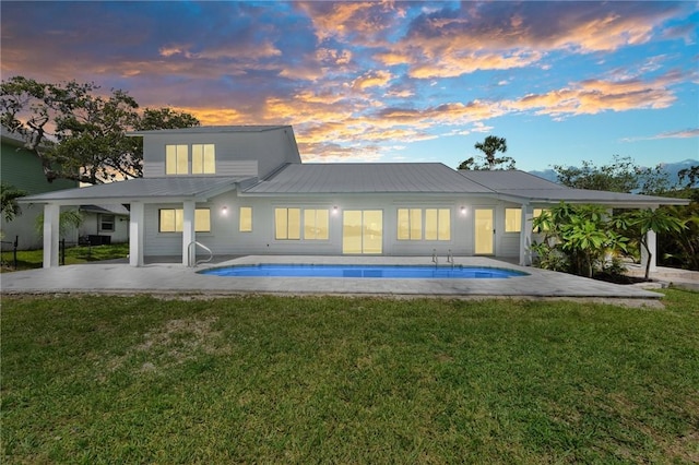 9670 Riverview Dr, Micco, FL 32976 - back of property at dusk featuring a patio, an outdoor pool, a yard, and a metal roof