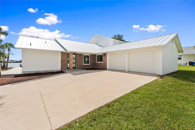 9670 Riverview Dr, Micco, FL 32976 - ranch-style house with a garage, a standing seam roof, concrete driveway, a front yard, and a metal roof