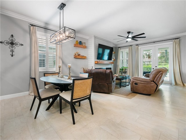 dining area with ceiling fan with notable chandelier, a large fireplace, and crown molding