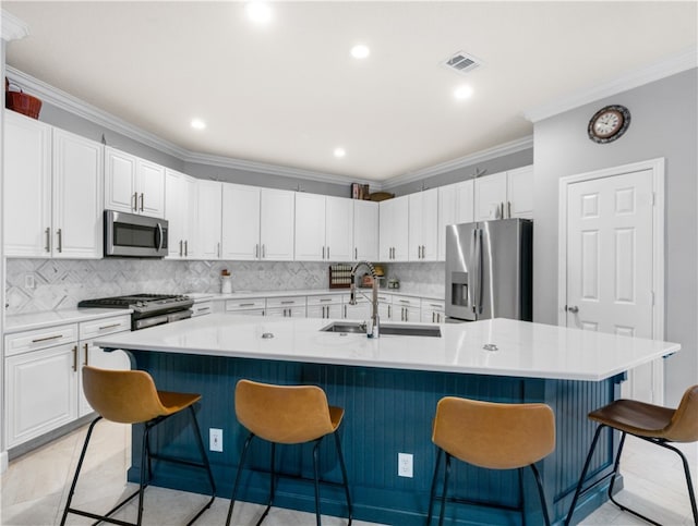 kitchen featuring stainless steel appliances, a kitchen breakfast bar, an island with sink, and ornamental molding