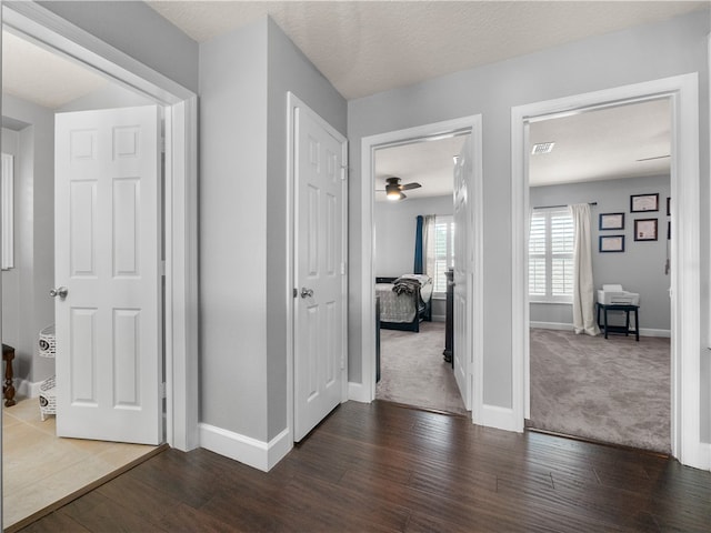 hall with dark wood-type flooring and a textured ceiling