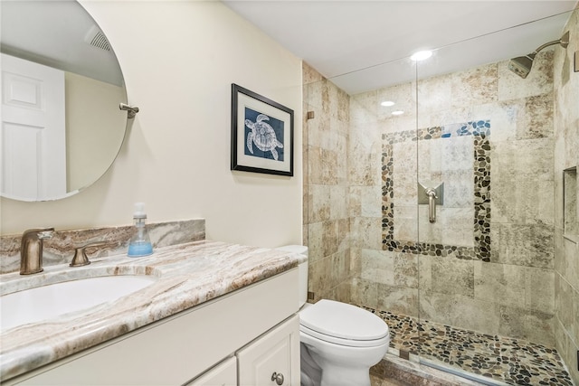 bathroom featuring toilet, vanity, and a tile shower