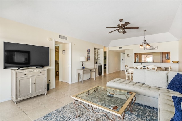 living room with ceiling fan with notable chandelier, light tile patterned floors, and vaulted ceiling