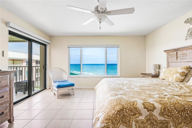 tiled bedroom featuring access to exterior, a water view, multiple windows, and ceiling fan