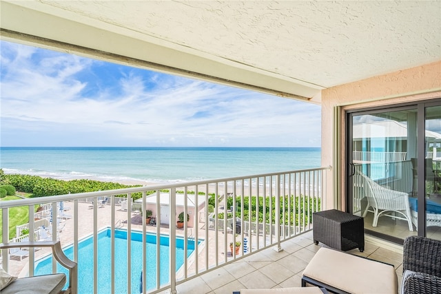 balcony featuring a view of the beach and a water view