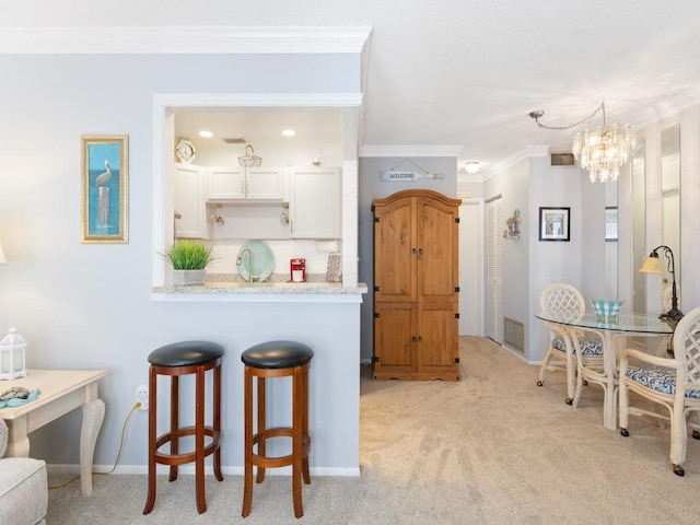 2800 Indian River Blvd Unit M7, Vero Beach, FL 32960 - kitchen featuring light colored carpet, a kitchen breakfast bar, ornamental molding, a chandelier, and white cabinets