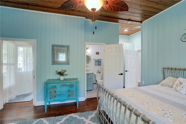 bedroom with connected bathroom, ceiling fan, dark hardwood / wood-style floors, wooden walls, and wood ceiling