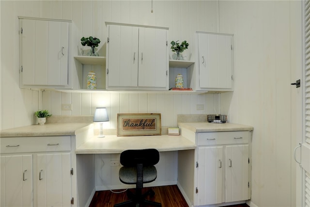 home office with dark hardwood / wood-style flooring and built in desk