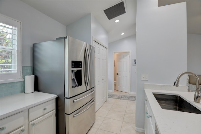 kitchen featuring white cabinets, light tile patterned floors, sink, and stainless steel refrigerator with ice dispenser