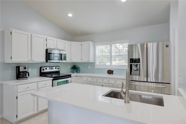 kitchen featuring appliances with stainless steel finishes, vaulted ceiling, white cabinetry, and backsplash