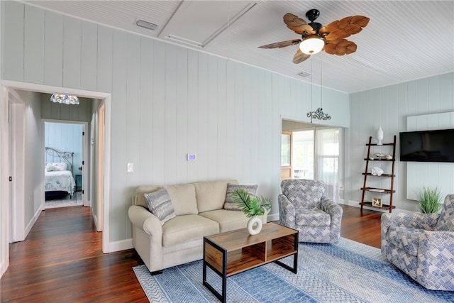 living room featuring dark hardwood / wood-style floors, ceiling fan, and wooden walls