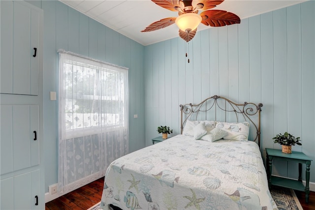 bedroom featuring hardwood / wood-style flooring, ceiling fan, and wooden walls