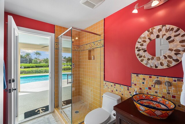 bathroom featuring tile walls, vanity, toilet, and a shower with shower door