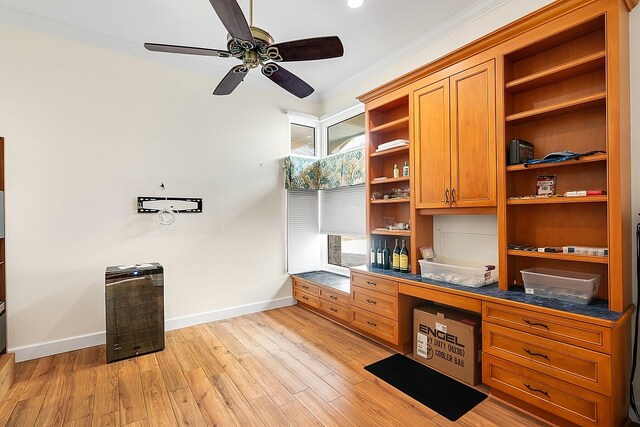 home office featuring built in desk, ceiling fan, light hardwood / wood-style flooring, and ornamental molding