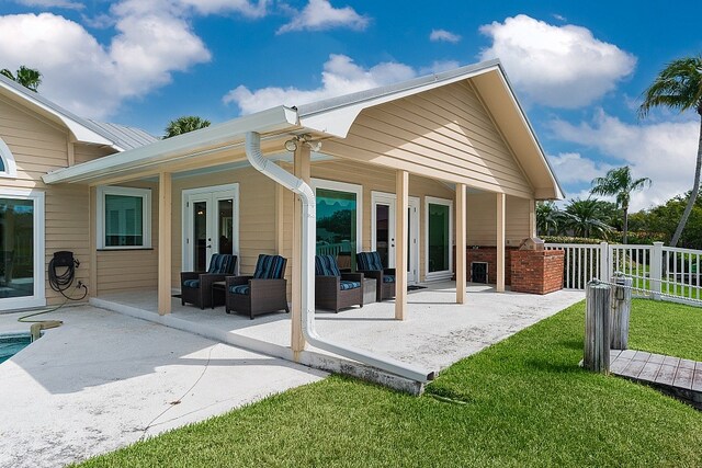 back of house featuring french doors, a lawn, and a patio area