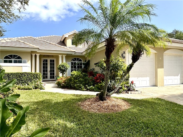 view of front of property with french doors, a garage, and a front lawn