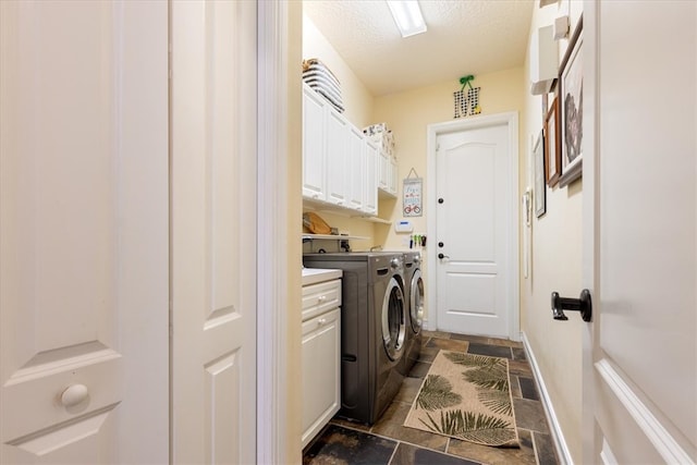 laundry area with washing machine and clothes dryer, cabinets, and a textured ceiling