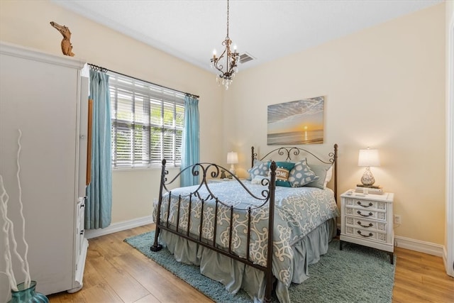 bedroom with light hardwood / wood-style flooring and a notable chandelier