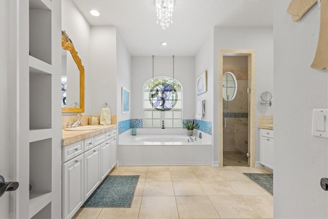 bathroom featuring tile patterned flooring, a notable chandelier, shower with separate bathtub, and vanity