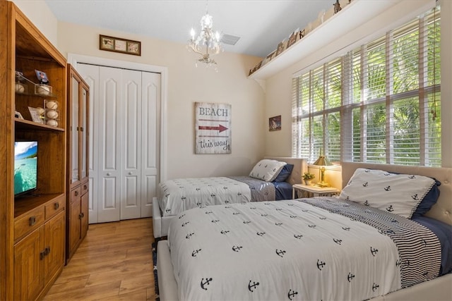 bedroom with light wood-type flooring, a chandelier, and a closet