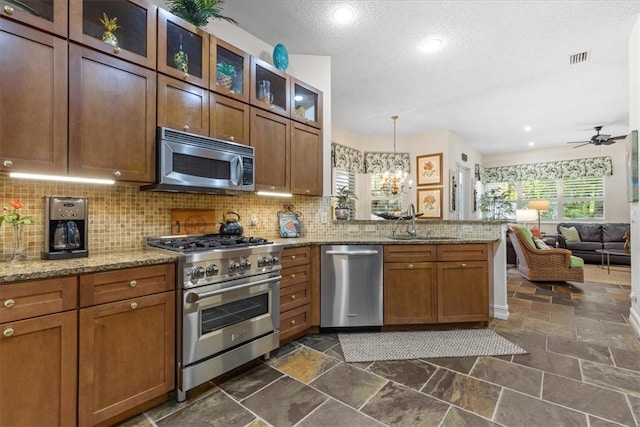 kitchen featuring light stone counters, stainless steel appliances, decorative light fixtures, decorative backsplash, and sink