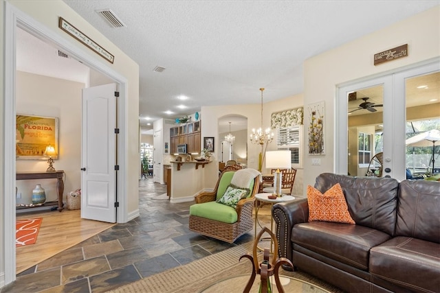 living room with dark hardwood / wood-style floors, a textured ceiling, and ceiling fan with notable chandelier