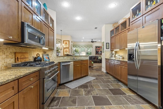 kitchen with decorative backsplash, pendant lighting, appliances with stainless steel finishes, and a textured ceiling