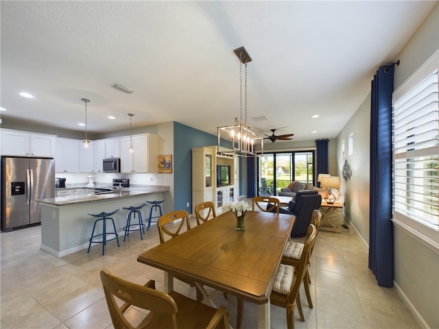 tiled dining space with ceiling fan with notable chandelier