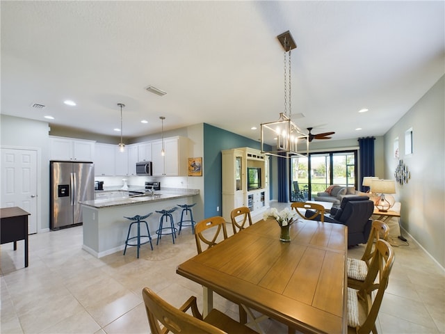 dining space with light tile patterned flooring and ceiling fan with notable chandelier