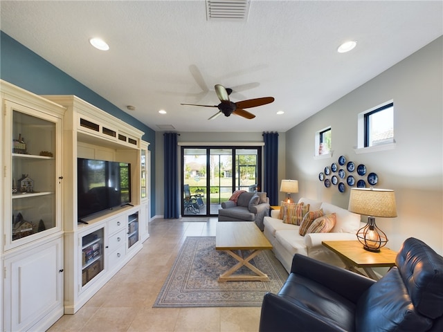 living room with a textured ceiling, a healthy amount of sunlight, ceiling fan, and light tile patterned floors