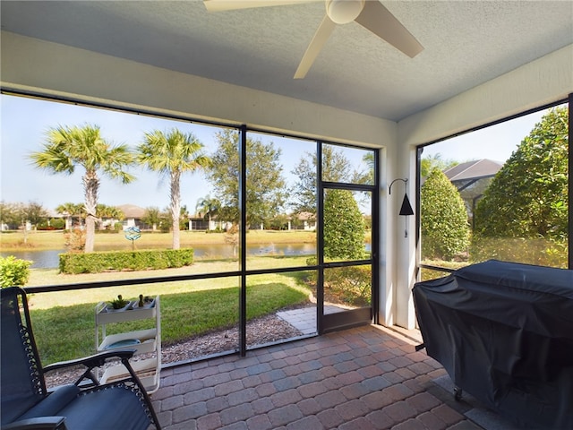 sunroom / solarium with ceiling fan and a water view