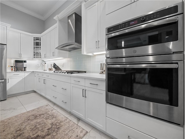 kitchen featuring white cabinets, stainless steel appliances, wall chimney exhaust hood, and ornamental molding