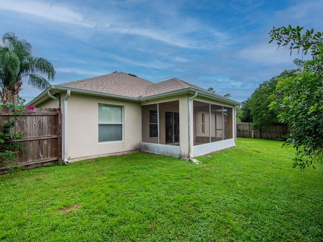 rear view of house featuring a sunroom and a lawn