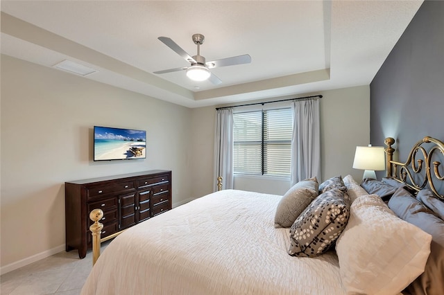 tiled bedroom featuring ceiling fan and a tray ceiling