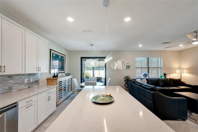 kitchen with dishwasher, white cabinets, hanging light fixtures, and plenty of natural light