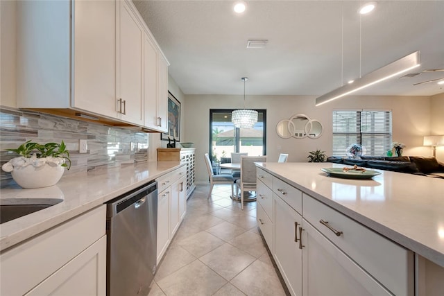 kitchen with tasteful backsplash, stainless steel dishwasher, a healthy amount of sunlight, decorative light fixtures, and white cabinetry