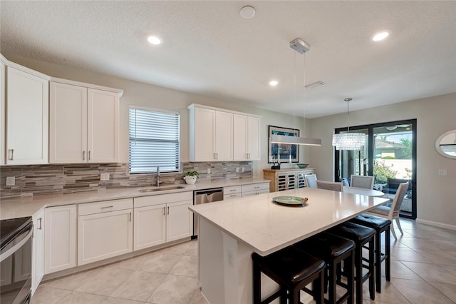 kitchen featuring pendant lighting, a center island, white cabinetry, and sink