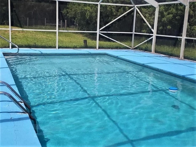 view of swimming pool featuring glass enclosure and a lawn