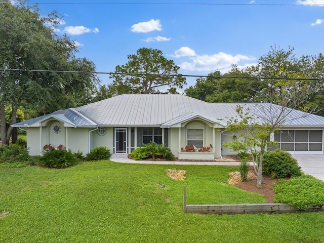 ranch-style house with concrete driveway, a front yard, an attached garage, metal roof, and stucco siding