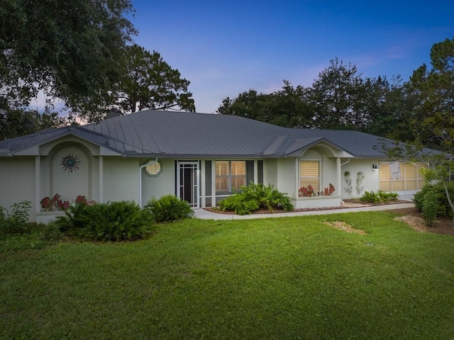 ranch-style house with stucco siding, a front lawn, and metal roof