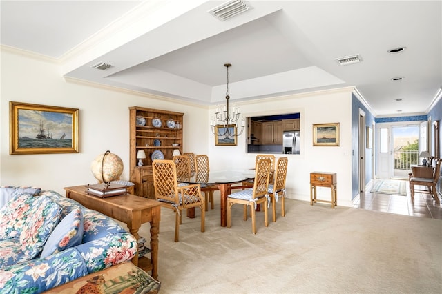 carpeted dining room featuring a notable chandelier, crown molding, and a tray ceiling