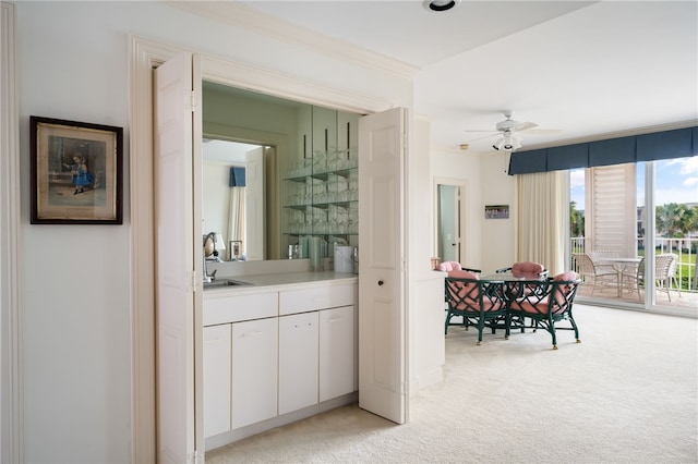 bar with white cabinets, ceiling fan, light colored carpet, and sink