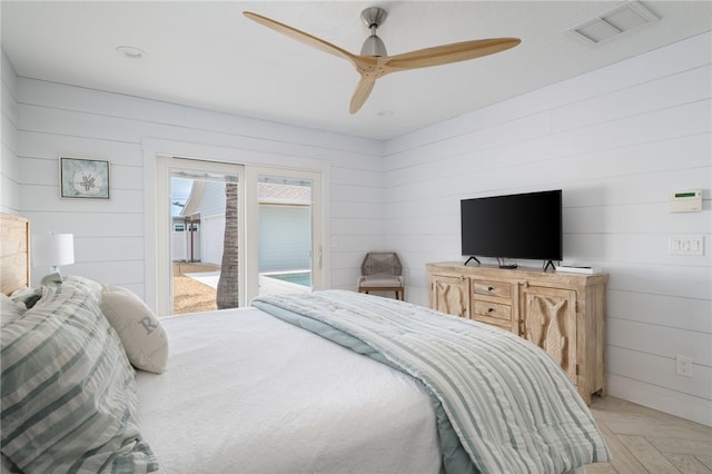 bedroom with access to exterior, light parquet floors, ceiling fan, and wood walls