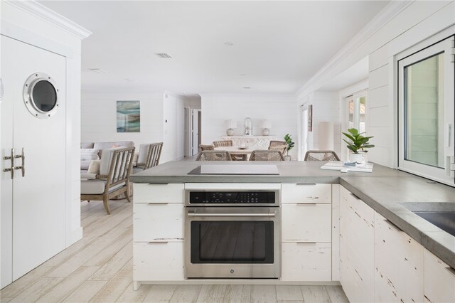 kitchen featuring stainless steel oven, black electric stovetop, crown molding, light hardwood / wood-style floors, and white cabinetry